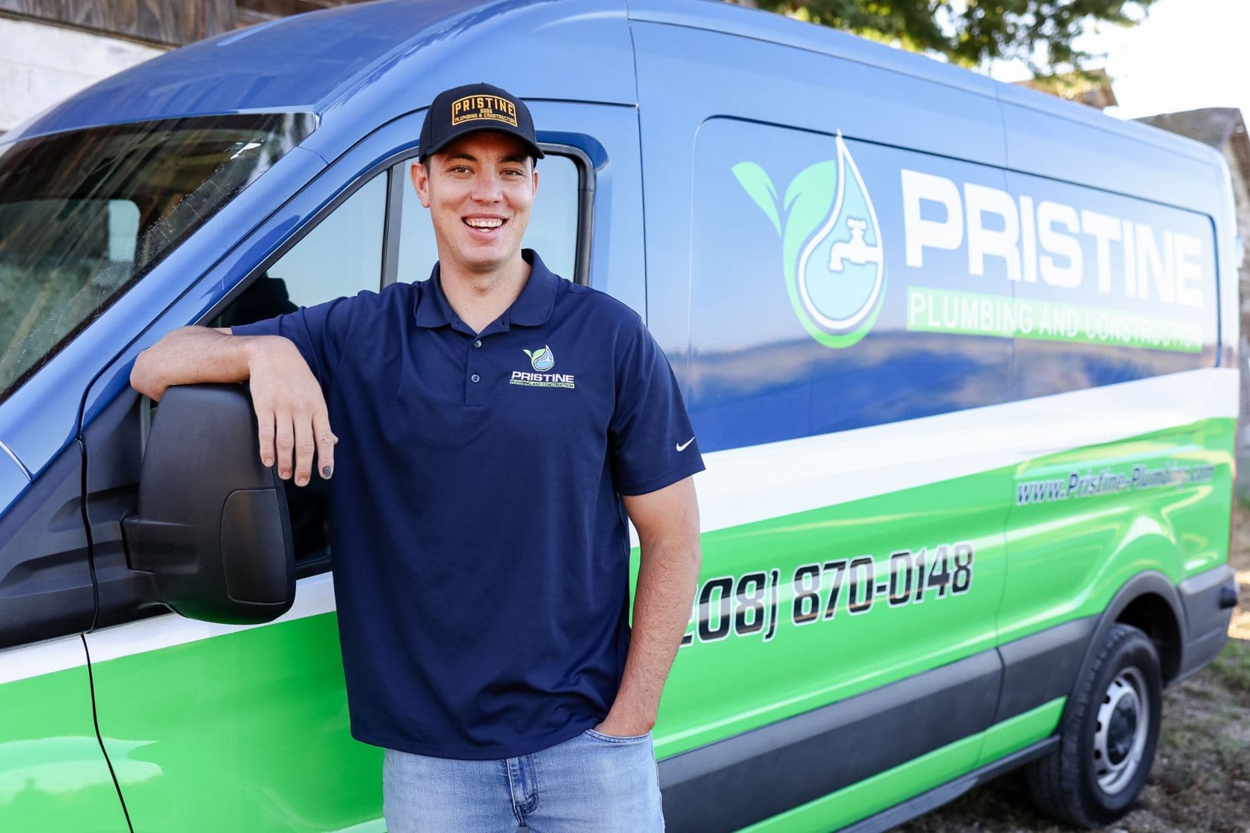 A Pristine Plumbing technician beside a branded service van in Nampa, Idaho