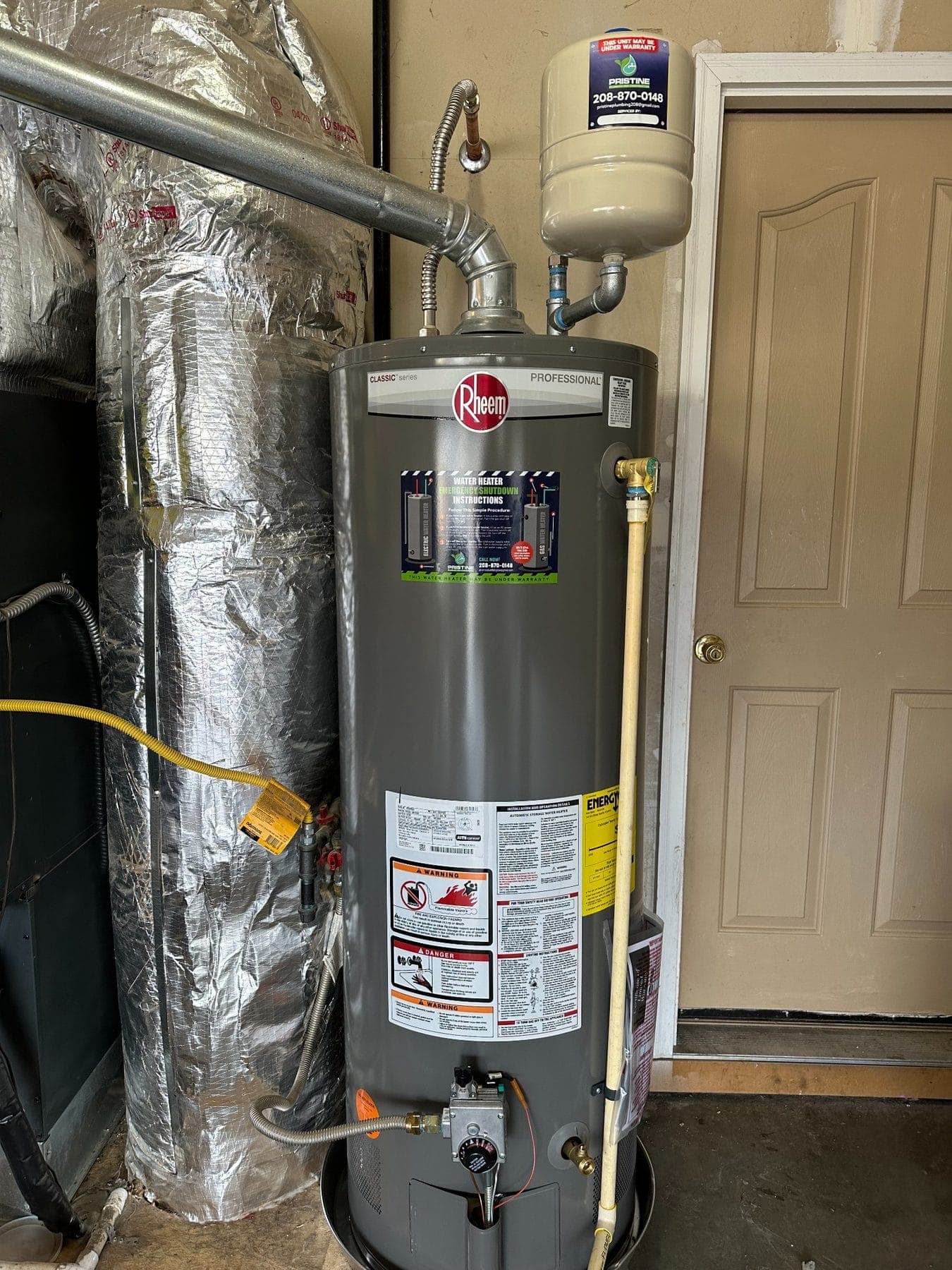 A newly installed Rheem gas water heater with expansion tank and a Pristine Plumbing service sticker