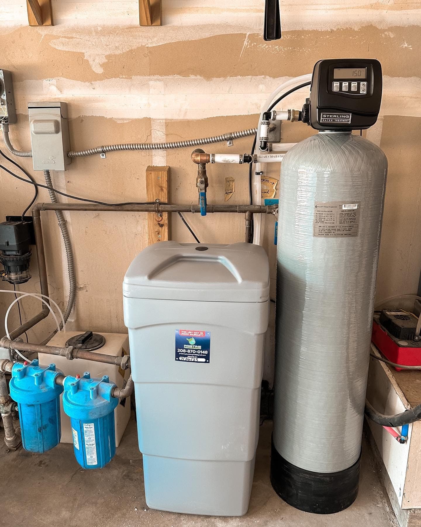 An installed water softener and brine tank with a Pristine Plumbing warranty sticker